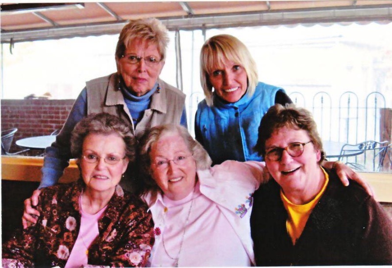 Group of five women. Three sitting, two standing behind.